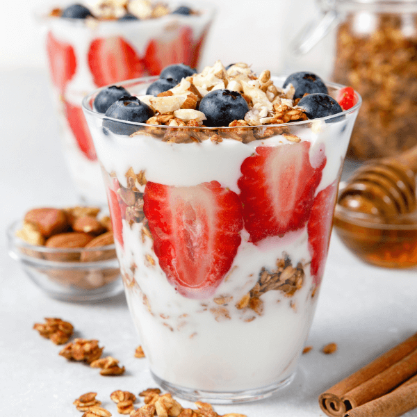 Granola Parfait with greek yogurt, oat granola, fresh berries, honey in tall glass jar. Healthy breakfast concept. Organic oat, almond and sunflower seeds.