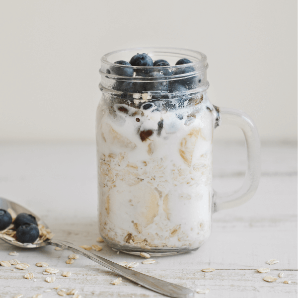 Overnight oats with whole grain cereal, fresh bluberries and coconut milk served with a spoon on wooden table. Healthy dessert for breakfast.