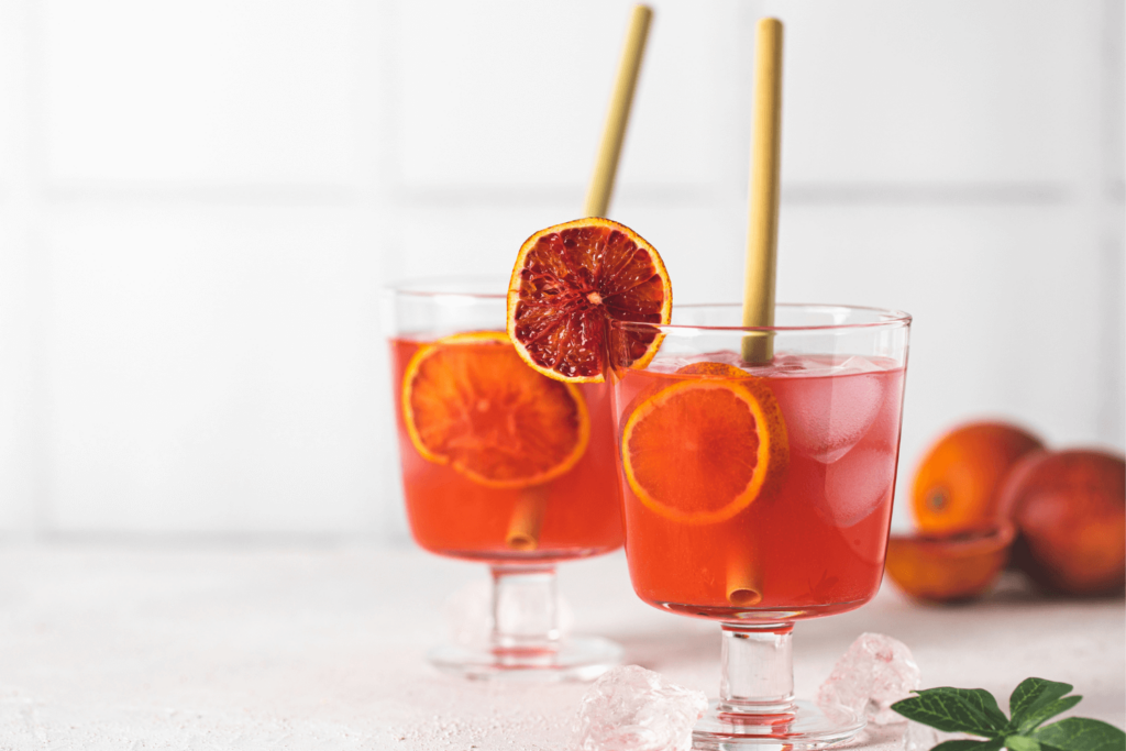 Two blood orange cocktails garnished with dehydrated blood orange wheel.