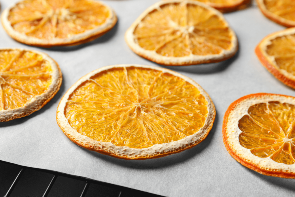 dehydrated oranges drying on a parchment paper-lined wire rack