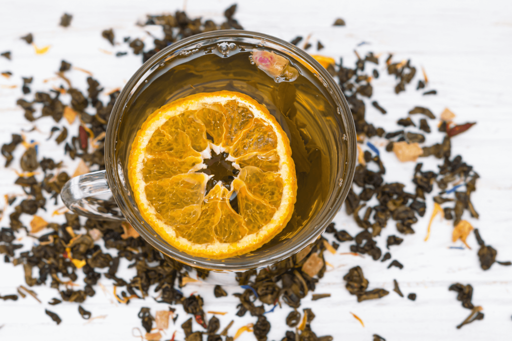 Overhead shot of glass cup of tea with dehydrated orange wheel floating in it.