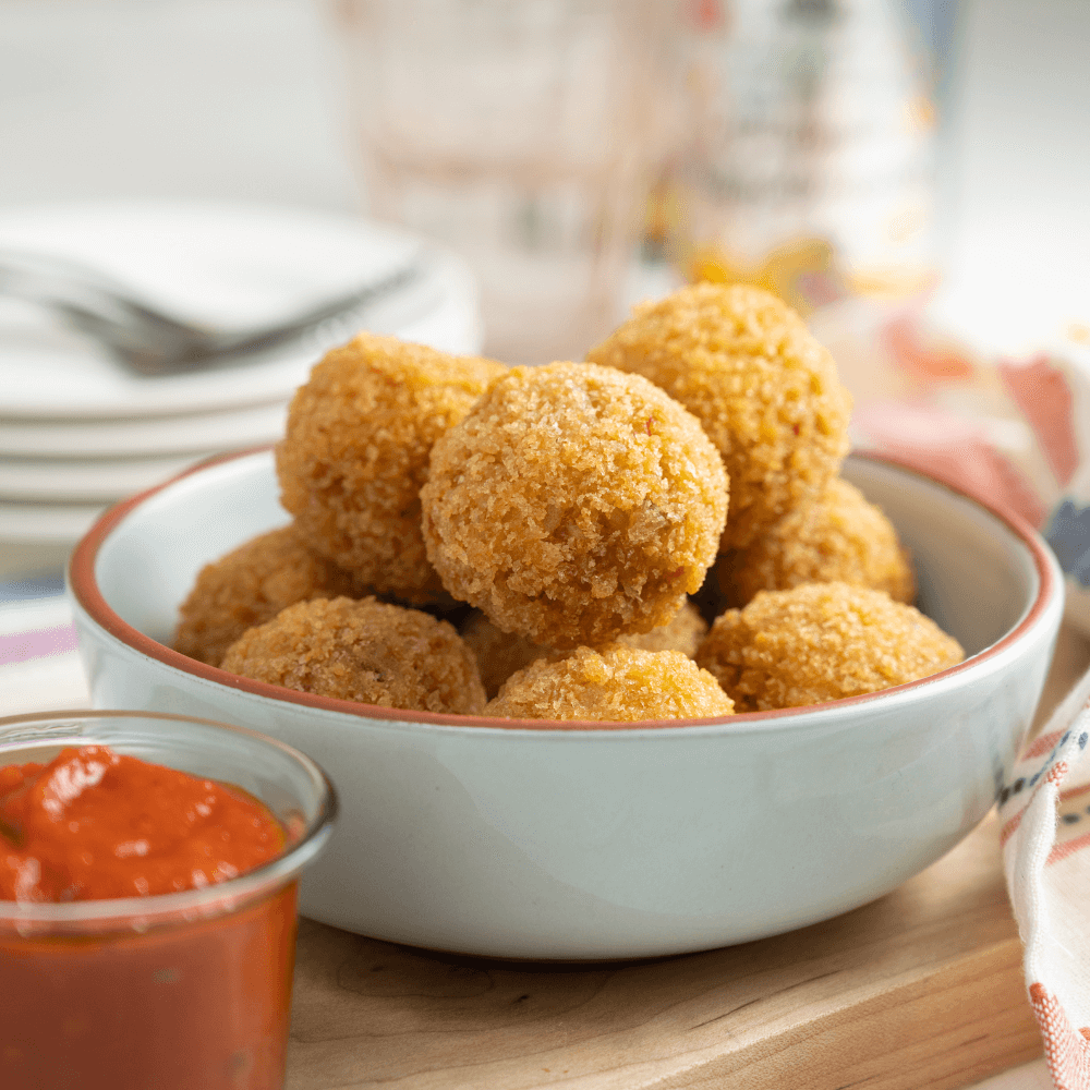 Bowl of Farm Boy Arancini with small glass serving bowl filled with Sugo di Pomodoro Tomato Sauce.