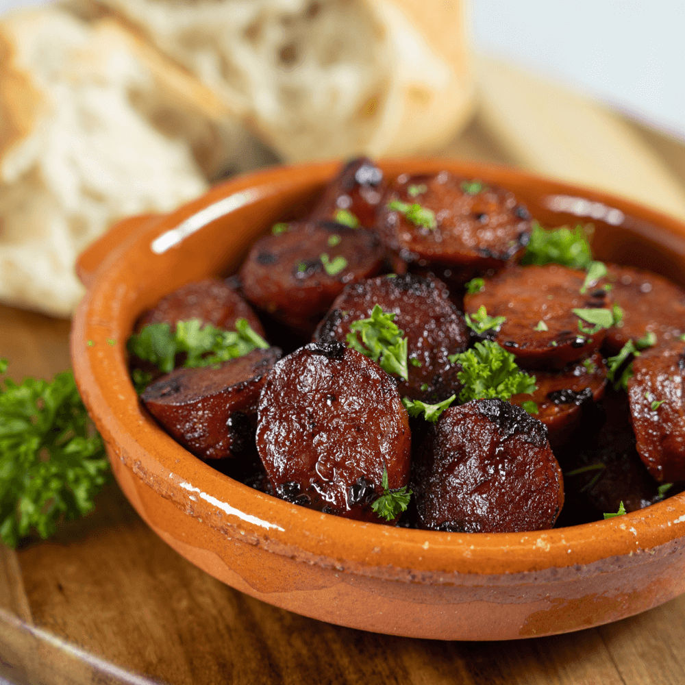 Holiday Appetizer Recipe: small stoneware bowl of red wine braised chorizo sausage garnished with fresh parsley.