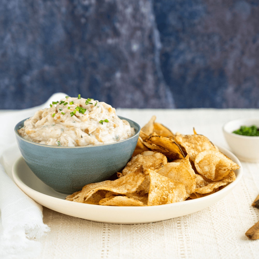 Holiday Appetizer Recipe: plate with kettle cooked chips and blue bowl of caramelized onion dip.