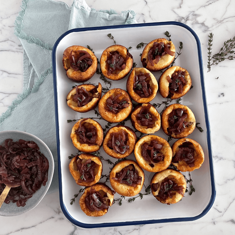 Holiday Appetizer Recipes: overhead image of rectangular serving platter with mini toads-in-a-hole filled with jammy balsamic onions.