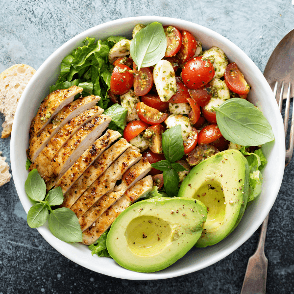 Overhead shot of Caprese Chicken Salad with avocado, grilled chicken, tomatoes, and spinach.