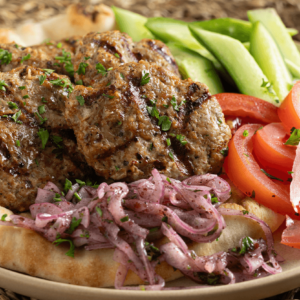Turkey Kofte with Sumac Onions and Toppings served on a plate.