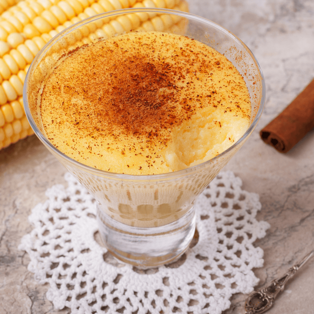 Parfait glass of Brazilian sweet corn custard pudding with sprinkle of cinnamon.