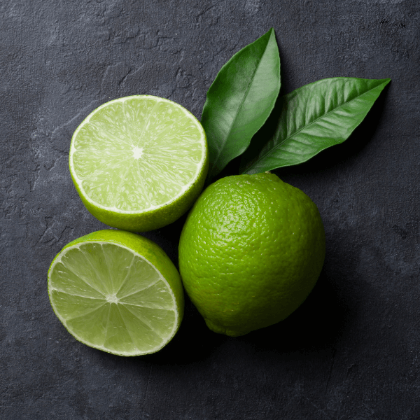 Whole and sliced lime on black slate background