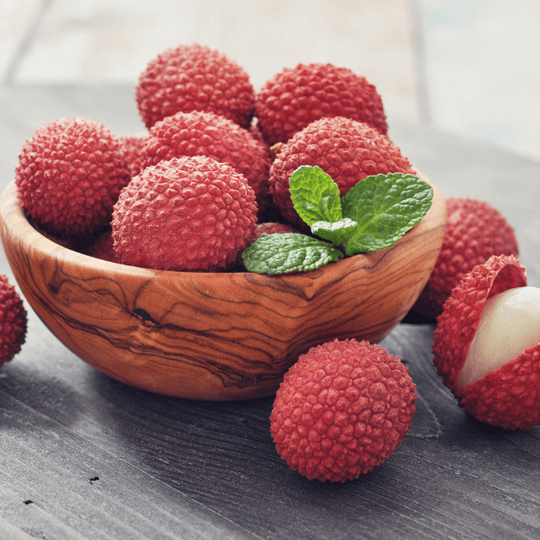 Wooden bowl of lychee fruits on wooden table.