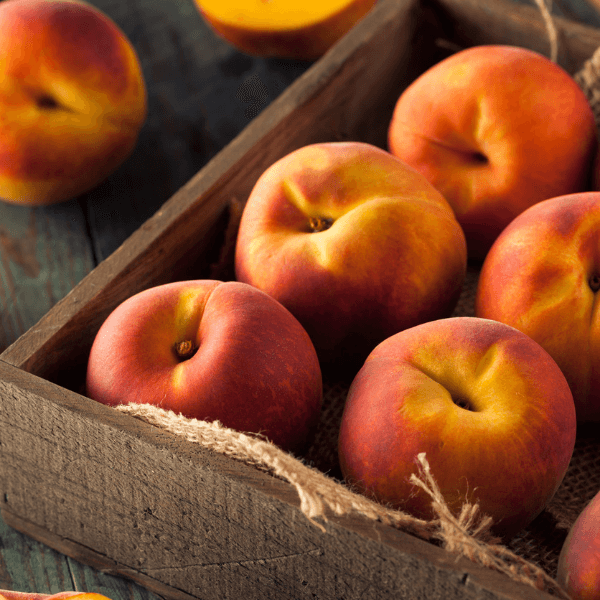 Wooden box with burlap filled with fresh peaches.