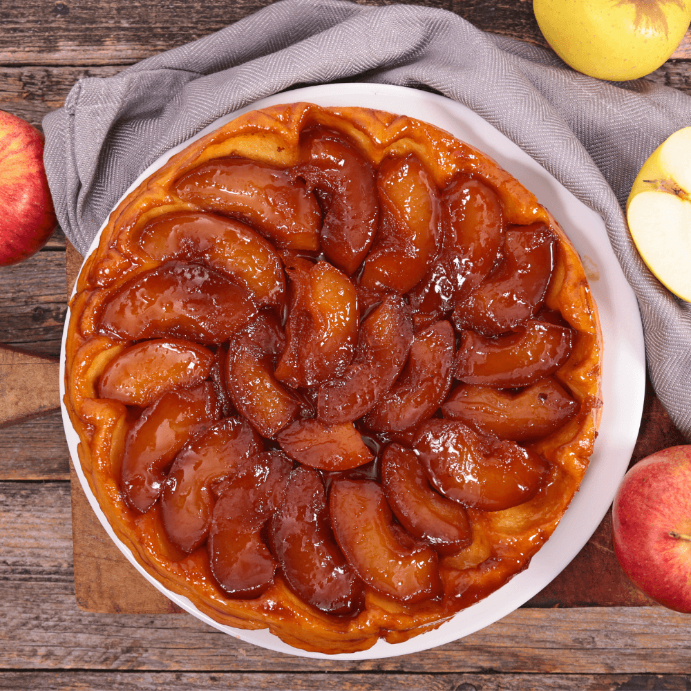 Above view of a round plate with a tarte tatin on a wooden table.