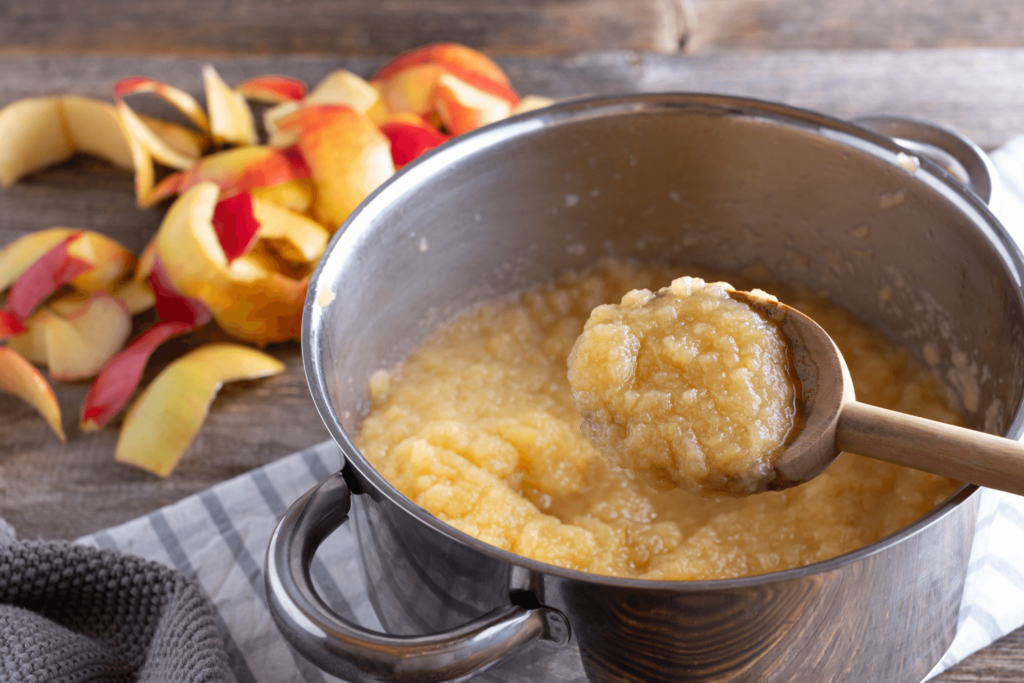 Traditional fresh cooked applesauce. Served in a saucepan and wooden spoon on rustic table.