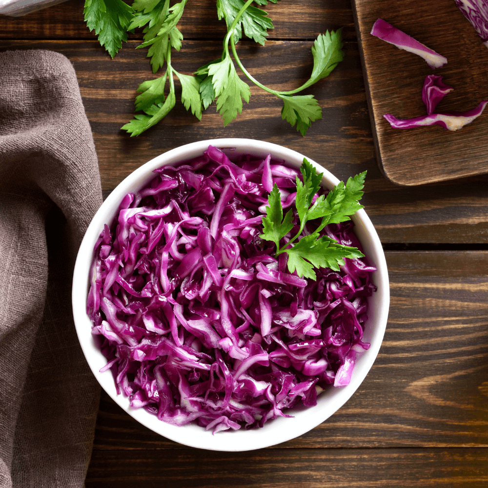 Above shot of red cabbage in white bowl on wooden table.