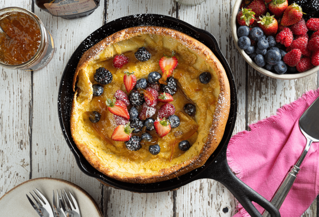 Overhead image of cast iron skillet with dutch baby pancake topped with fresh berries.