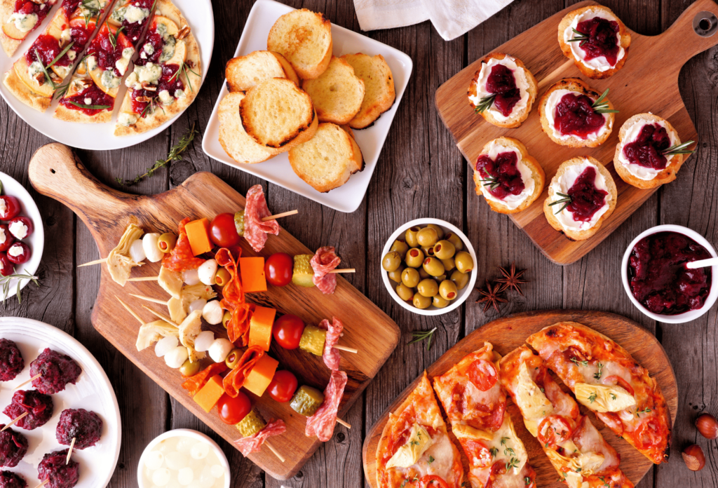 Winter holiday theme appetizers. Top down view table on a dark wood background. Flatbreads, skewers, cranberry crostini and different party food.