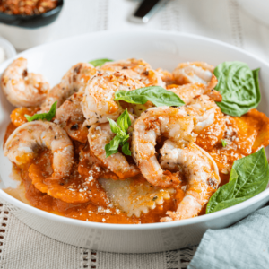 Bowl of hearty Spicy Shrimp Pasta with cooked shrimp and fresh basil leaves from Farm Boy